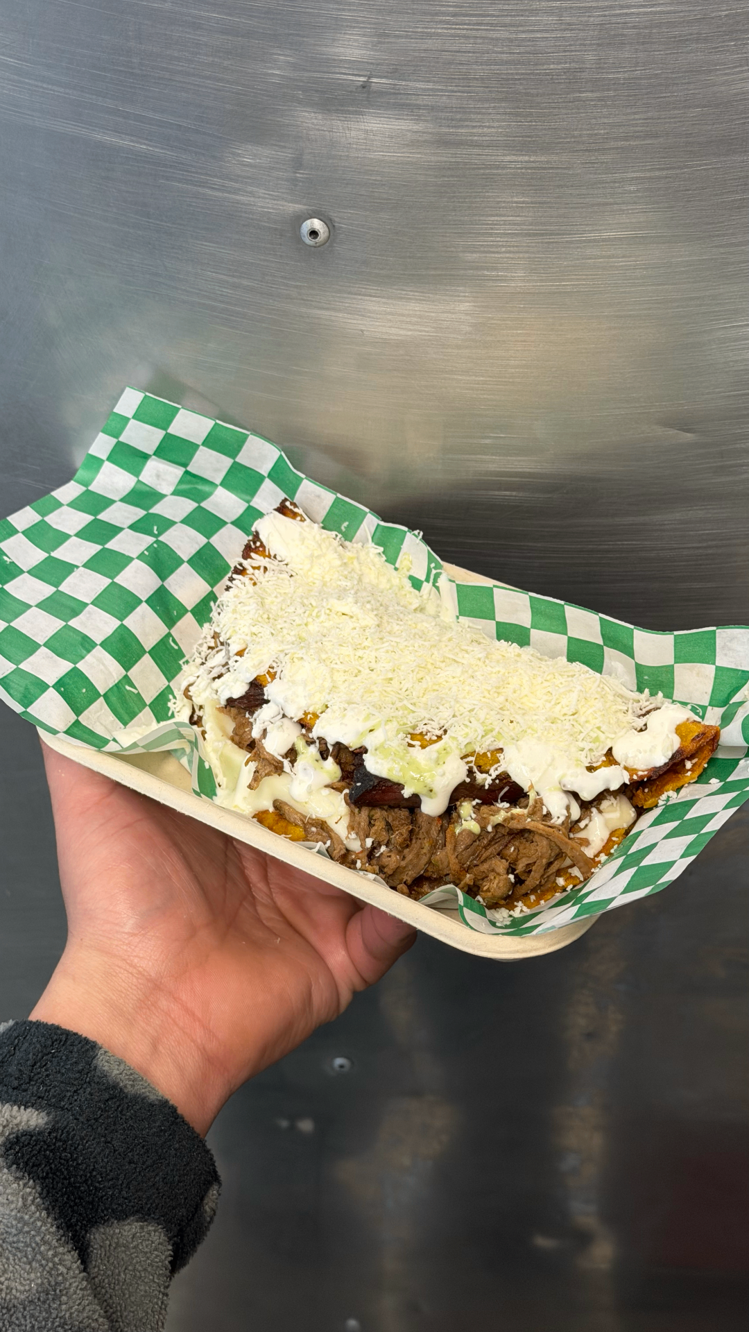 Patacón platter topped with shredded beef, sauce, and cheese